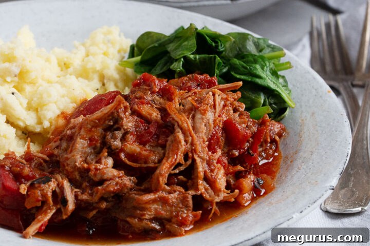 Pork arrabbiata on plate with mashed potatoes and spinach