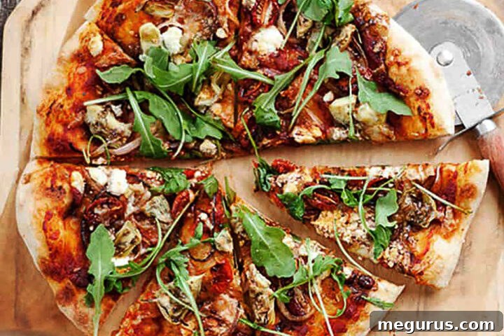 Roasted vegetable pizza sliced on a pizza peel with fresh arugula