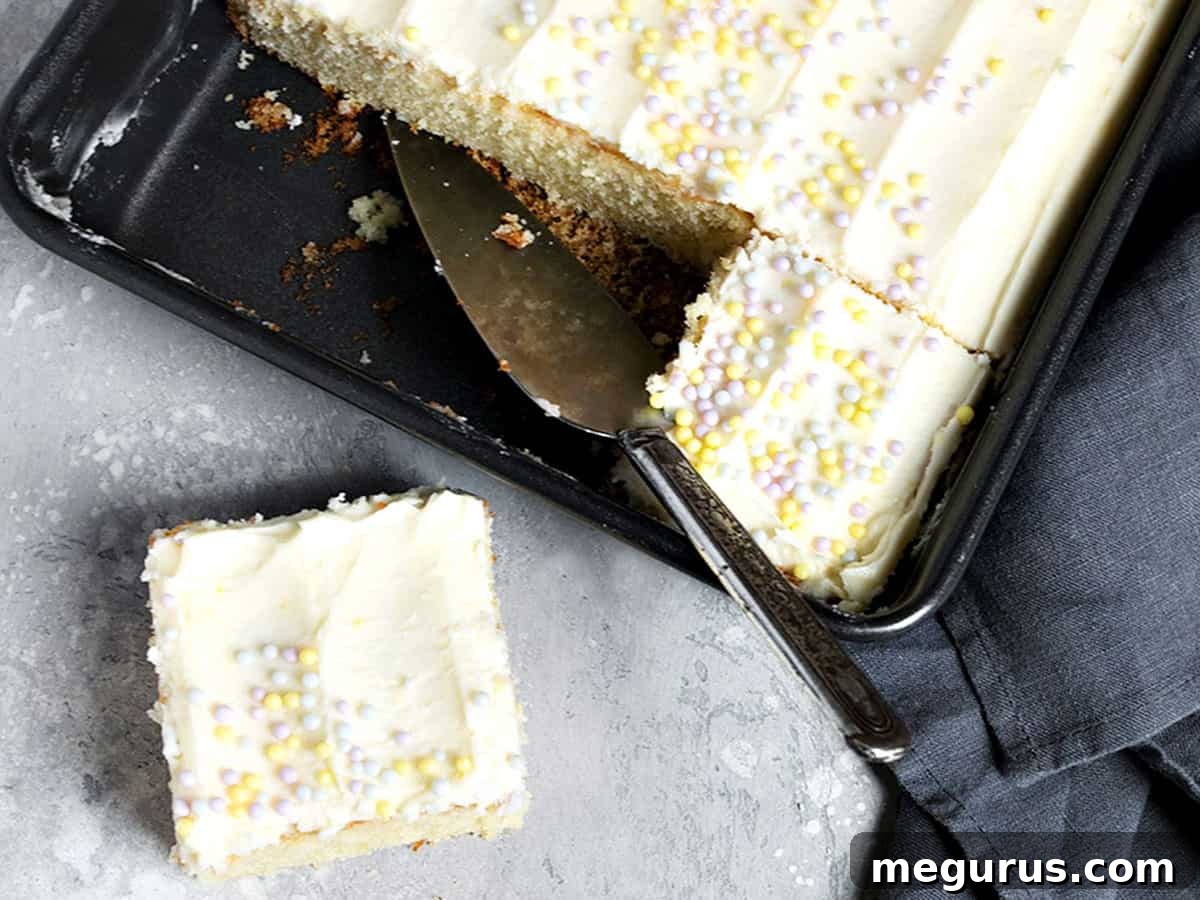 A beautifully frosted lemon sheet cake with one slice neatly cut out, showcasing its moist texture and vibrant lemon flavor.