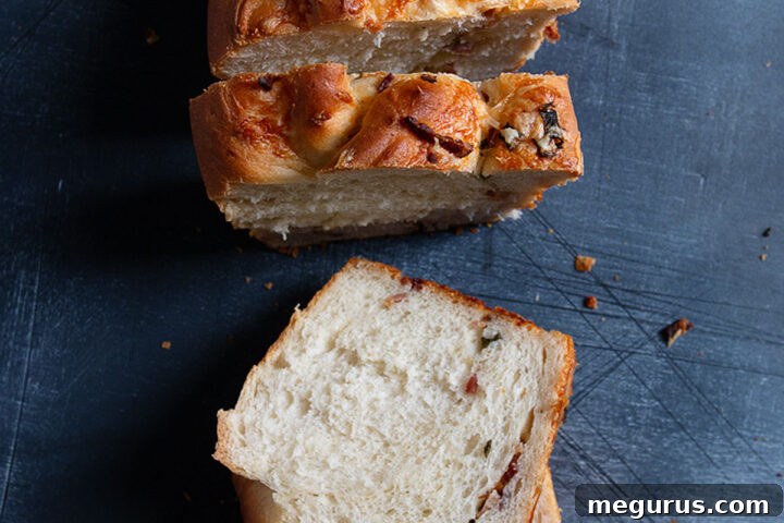 Baked potato bread sliced, showing the rich filling of cheese, bacon, and green onion