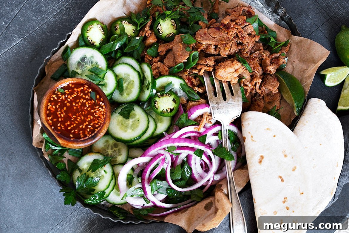 Spicy Korean pork tenderloin cooking in a pan, surrounded by fresh toppings and warm tortillas