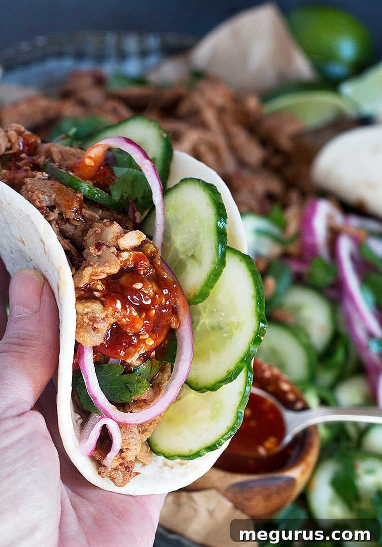 Close-up of a spicy pork tenderloin taco topped with fresh vegetables and sauce