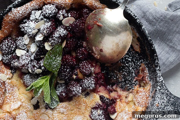 blackberry Dutch baby in cast iron skillet with spoon