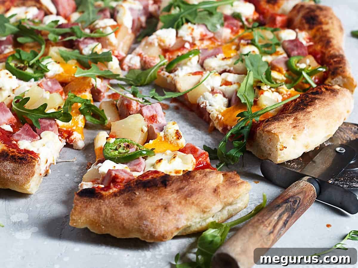 Delicious three cheese Hawaiian pizza sliced, ready to be served, showcasing chunks of ham, pineapple, and melted cheeses.