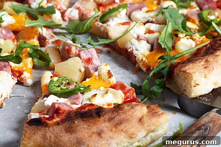 Three cheese Hawaiian pizza sliced, with ham, pineapple, and jalapeños visibly topping the cheesy surface.