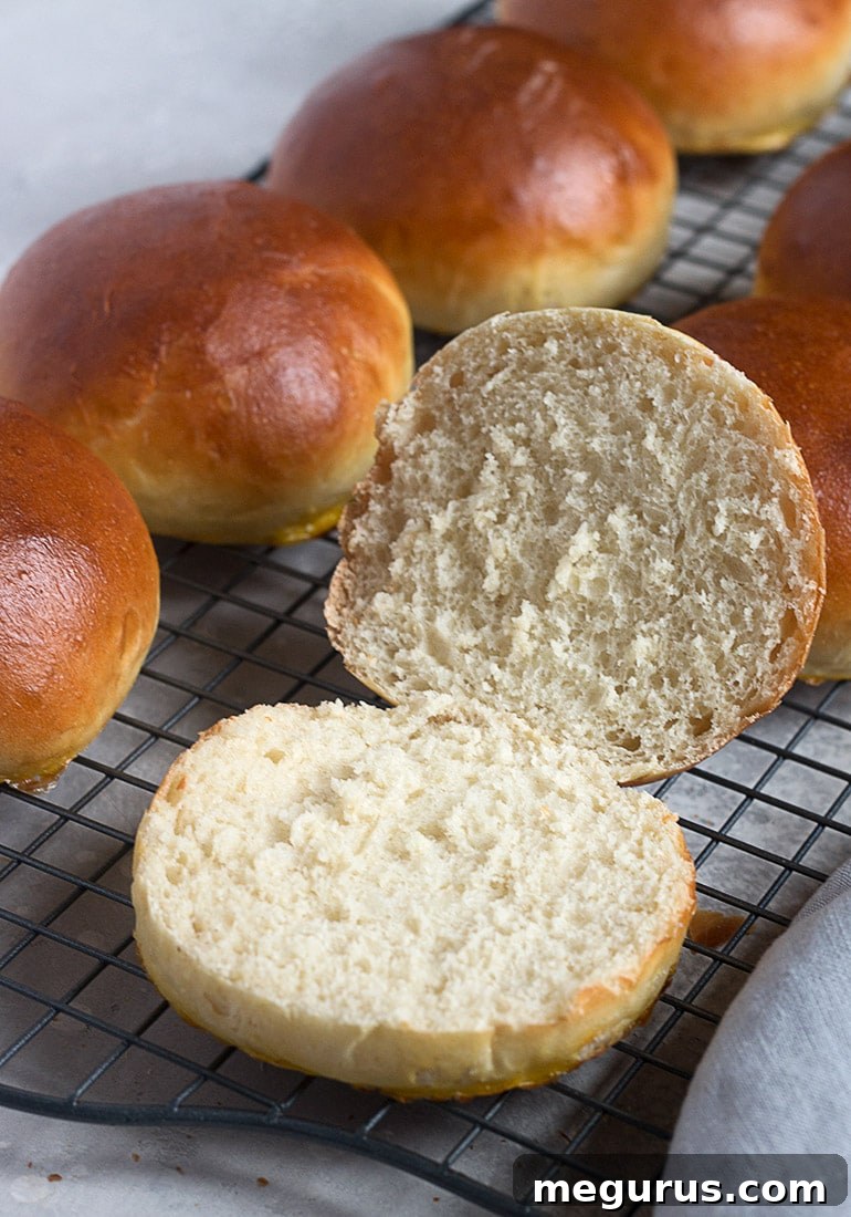 A close-up of homemade hamburger buns on a cooling rack, showcasing their golden tops