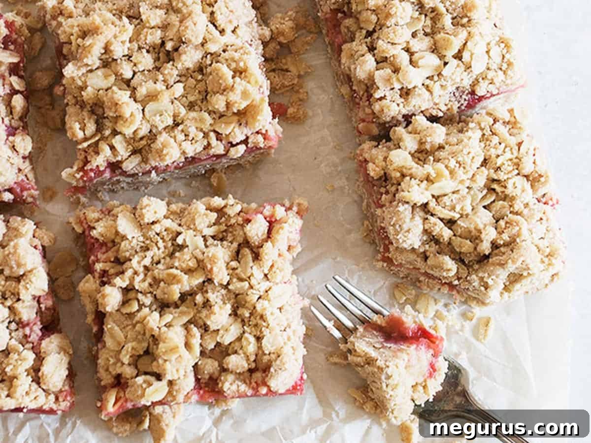 Delicious strawberry rhubarb crumble squares cooling on parchment paper, ready to be sliced.