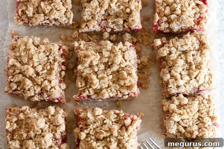 Close-up of a single strawberry rhubarb square, showing the crumbly topping and fruit filling.
