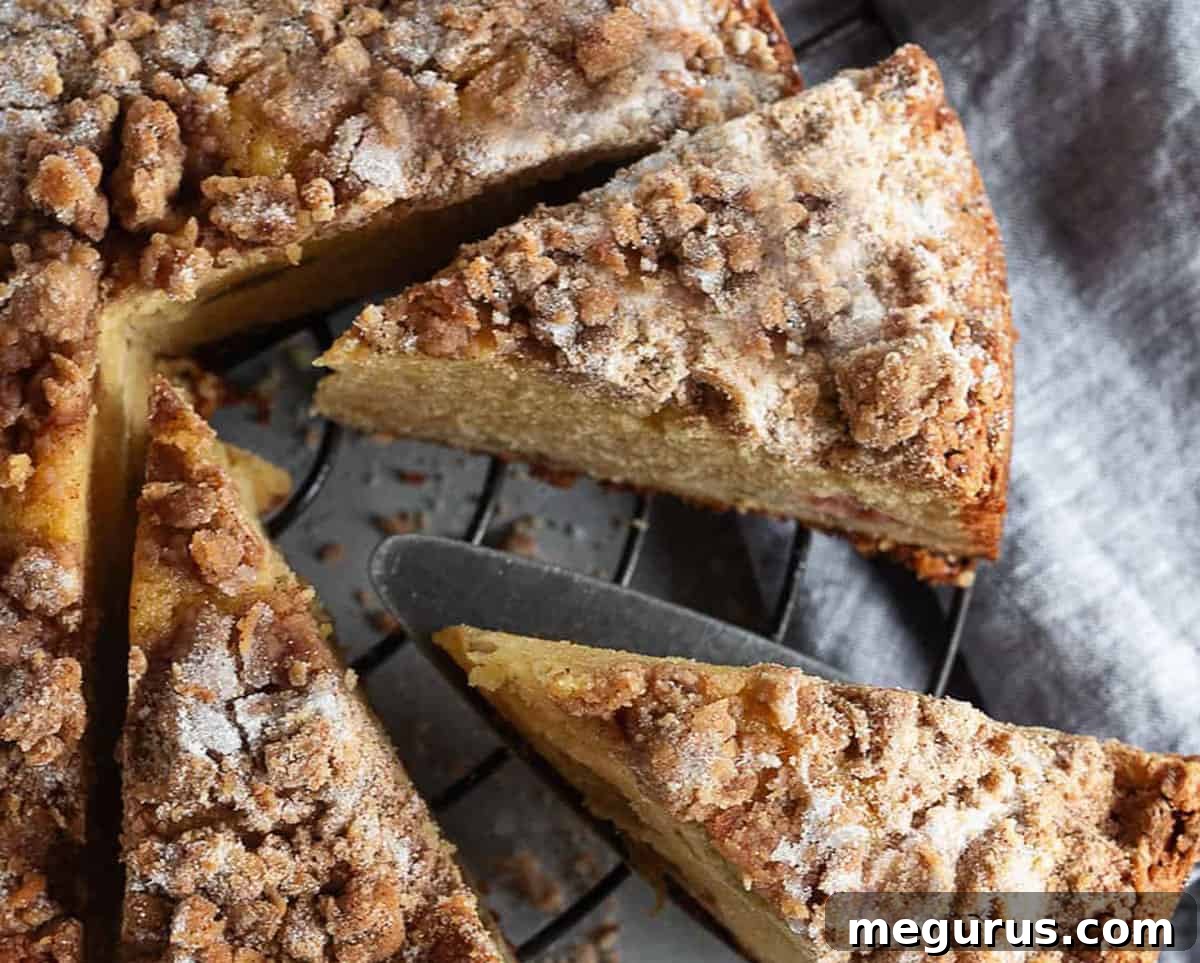 Rhubarb crumble cake on cooling rack sliced, showing the moist interior and crunchy topping.