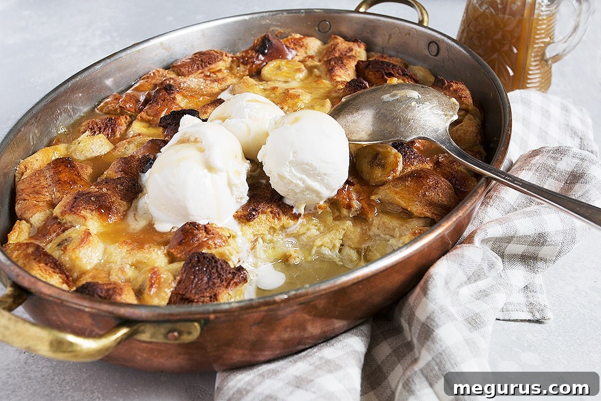 Warm Bananas Foster Bread Pudding in a baking dish, ready to be served, topped with creamy sauce