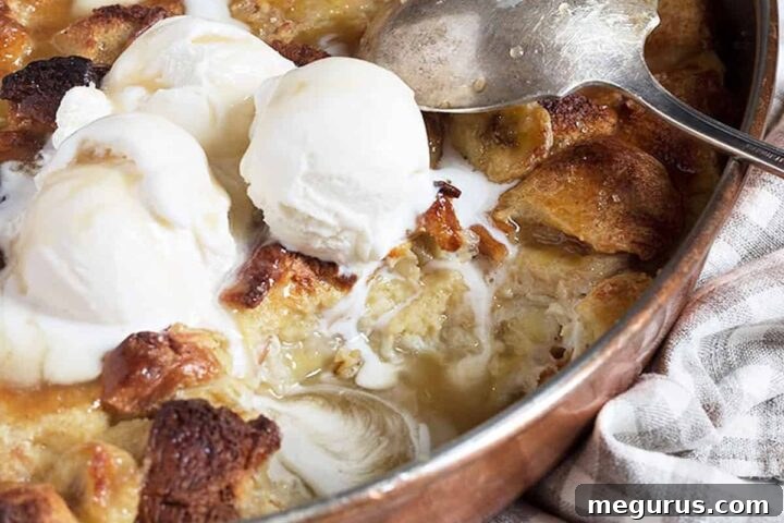Close-up of Bananas Foster Bread Pudding in a copper baking pan, with a scoop of vanilla ice cream