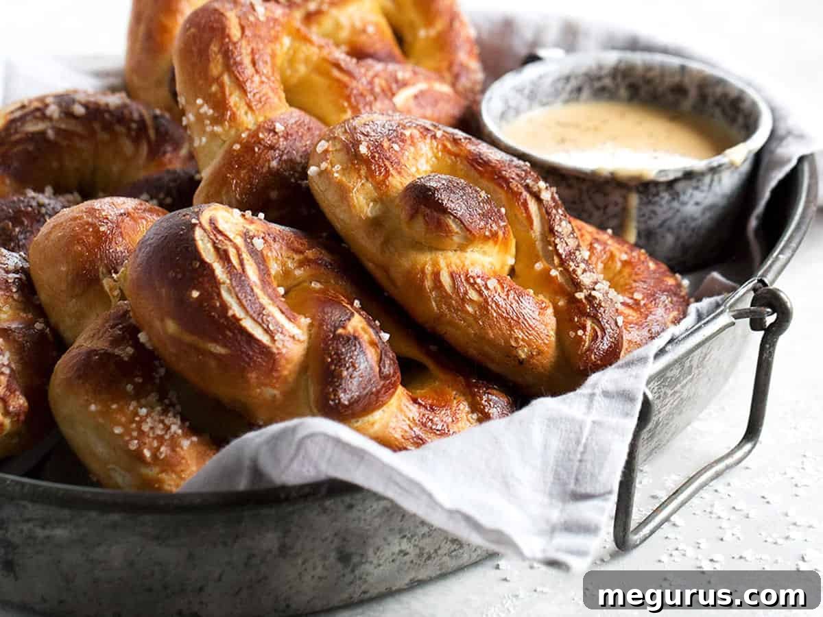 Soft, golden-brown homemade pretzels arranged on a tray, with a ramekin of creamy beer cheese dip beside them, ready for serving.