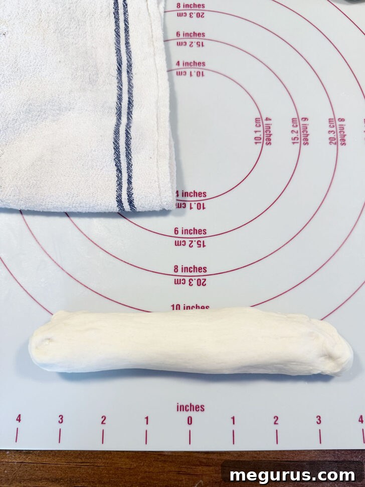 A dough ball stretched slightly into an oblong shape, the initial step for rolling a pretzel rope.