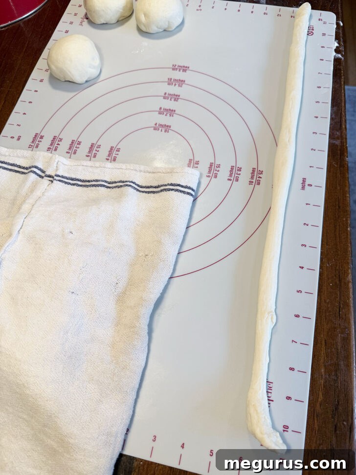 A fully rolled dough rope, approximately 24 inches long, ready for shaping into a pretzel.