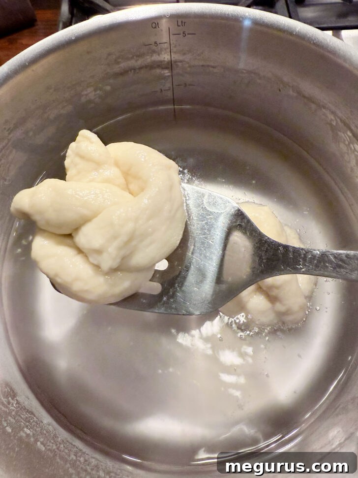 Two pretzels carefully removed from the baking soda bath, visibly puffed up and slightly textured.