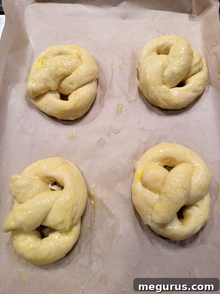 Pretzels on a baking sheet, brushed with egg wash and sprinkled with coarse salt, ready for the oven.