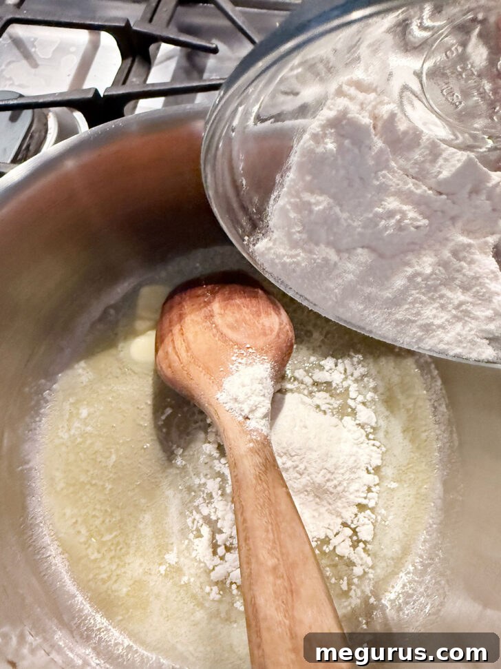 All-purpose flour being stirred into melted butter in a saucepan, forming a roux.