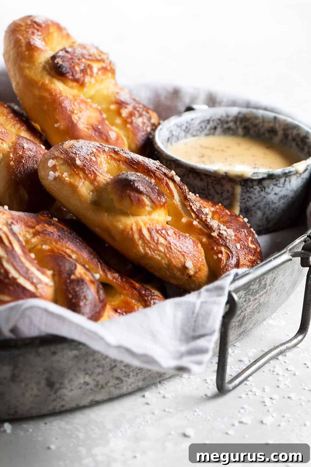 Close-up shot of freshly baked soft pretzels and a cup of beer cheese, highlighting their texture and golden crust.