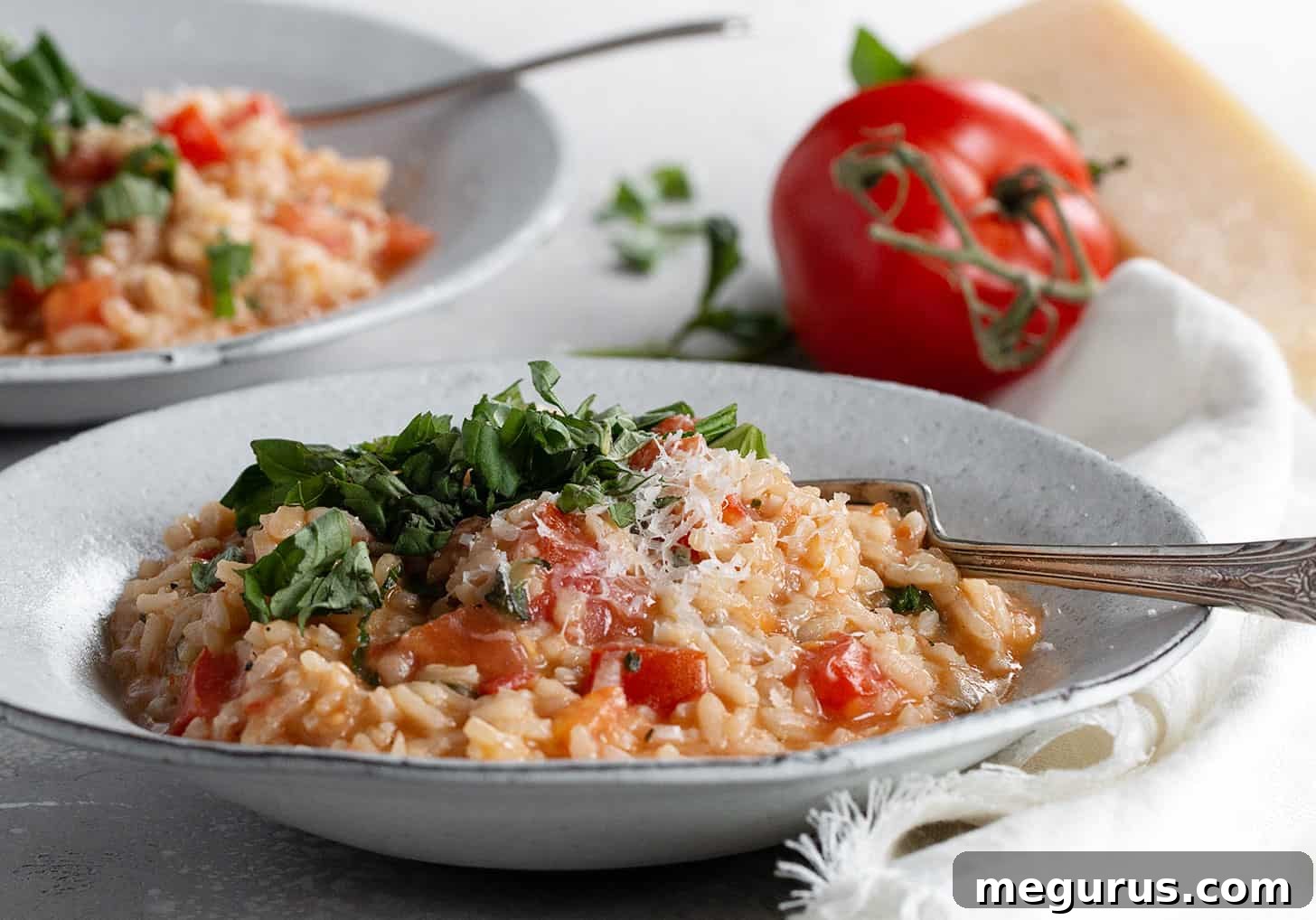 Lush tomato basil risotto in a bowl, garnished with fresh basil leaves and a fork resting beside it, suggesting a delightful meal.