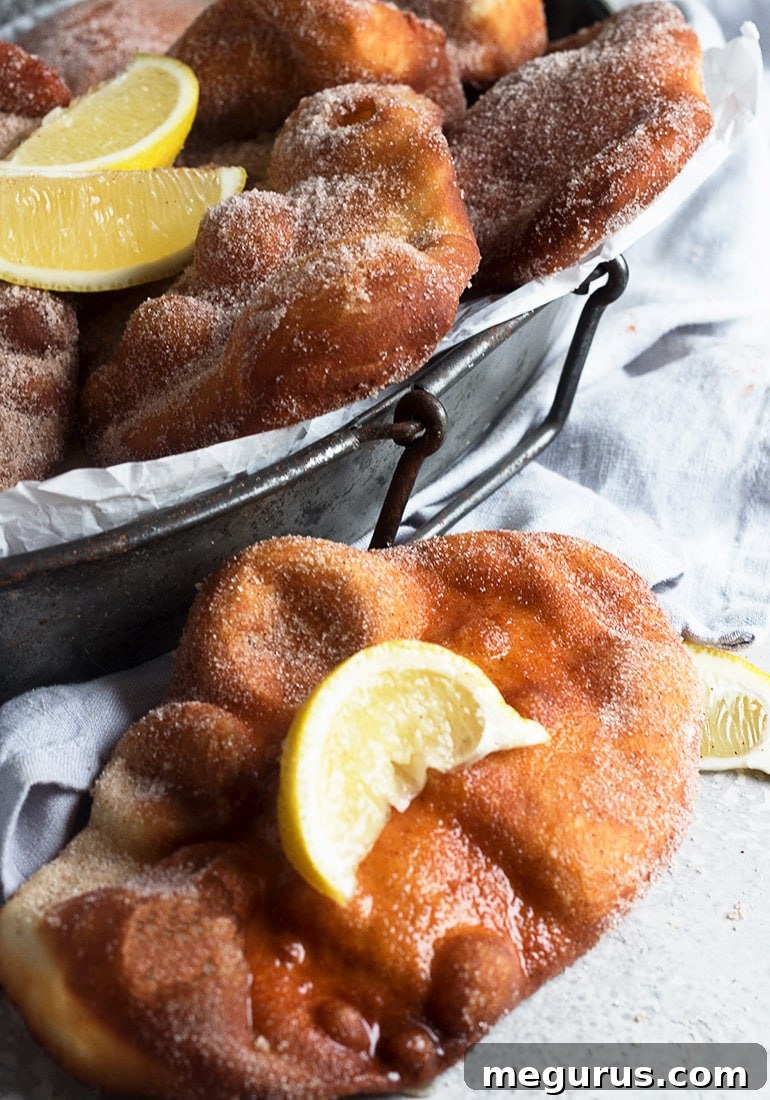 Freshly fried Canadian Beavertails stacked and ready for serving, showcasing the golden color and sugar coating.