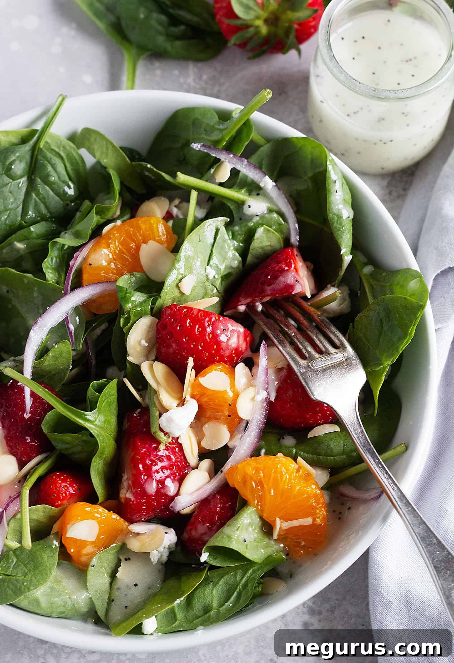 Close-up of the vibrant strawberry spinach mandarin salad, showcasing the poppy seed dressing drizzled over the ingredients.