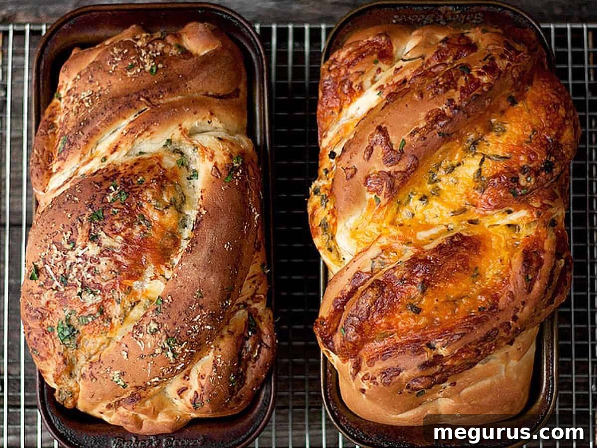 Two golden-brown loaves of homemade cheddar cheese bread in loaf pans, cooling on a wire rack.