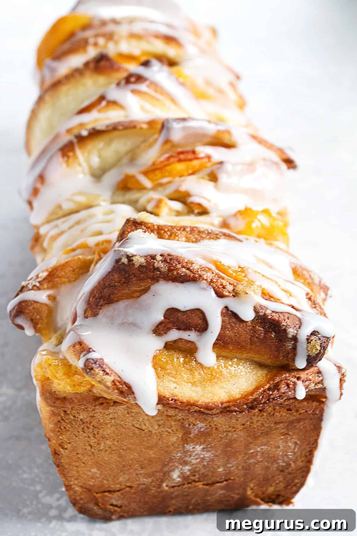 Glazed peach pull apart bread, showcasing its golden-brown crust and sweet vanilla drizzle.