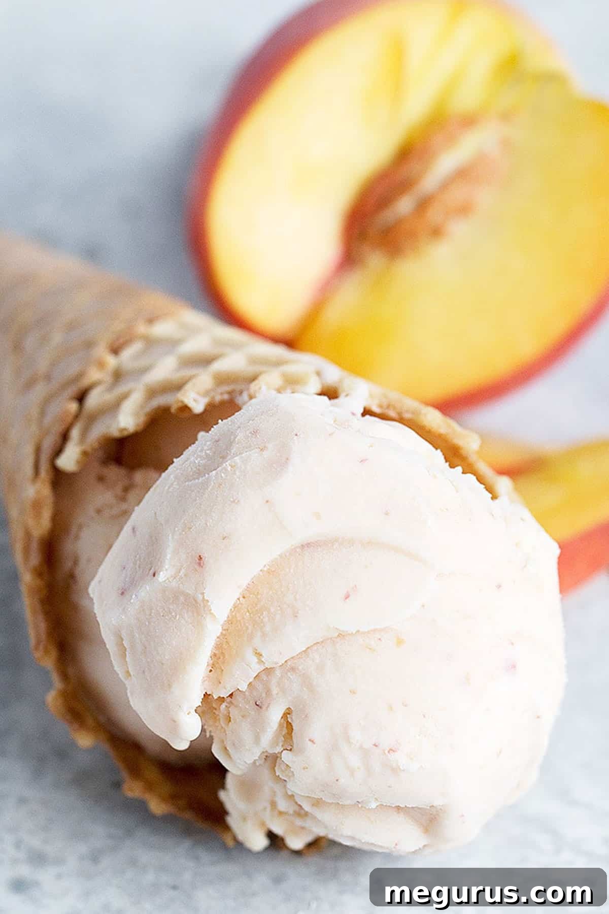 Close-up of peach ice cream in a waffle cone, showing creamy texture and subtle peach hues.