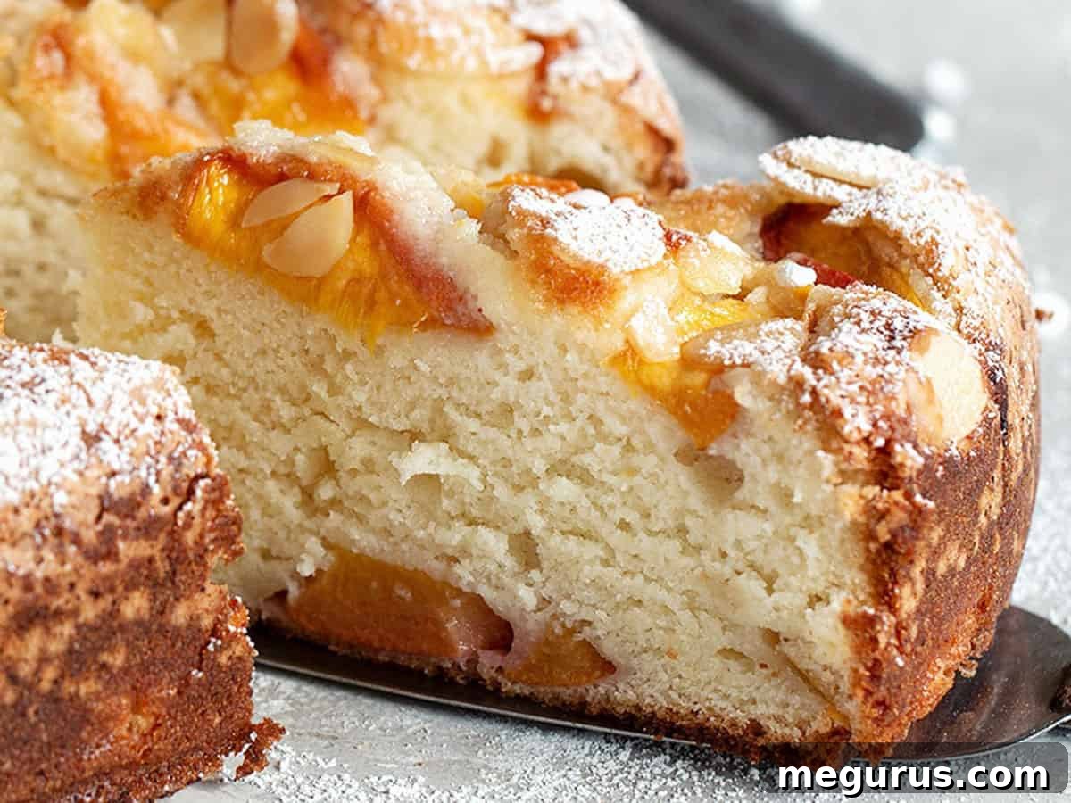 A beautifully sliced peach ricotta cake revealing its tender crumb and succulent peach pieces, perfect for a summer treat