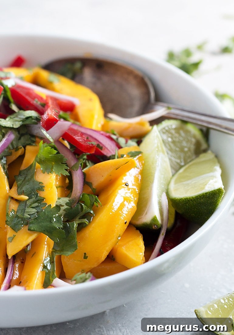 Close-up of mango salad in a bowl, showing the vibrant colors of mangoes, bell peppers, and fresh herbs.