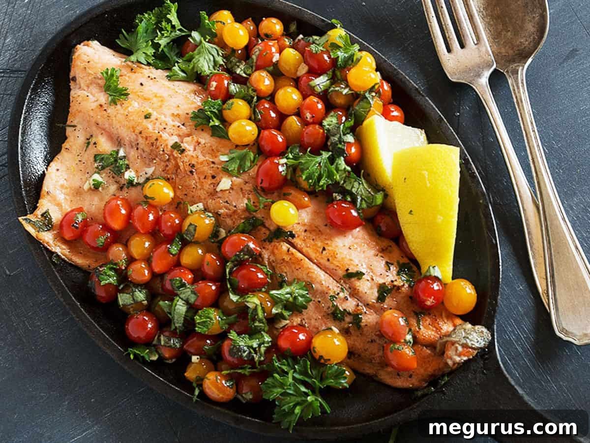 Pan-fried rainbow trout with vibrant mini cherry tomatoes in a cast iron skillet