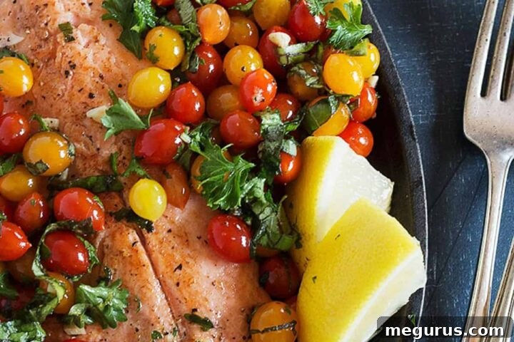 Succulent rainbow trout with bursting cherry tomatoes, garnished with fresh herbs in a skillet