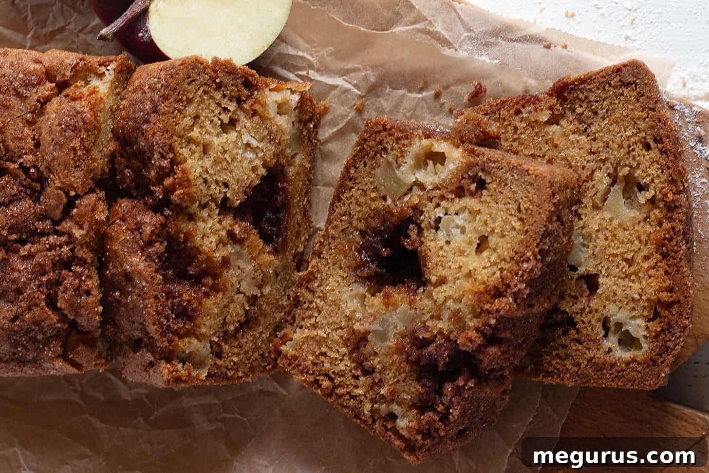 Sliced apple cinnamon loaf on parchment paper, showing streusel layers