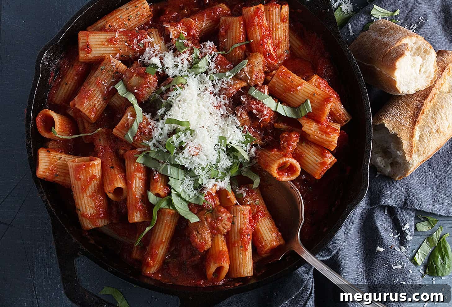 Italian sausage pasta in a rustic skillet, served alongside crusty bread