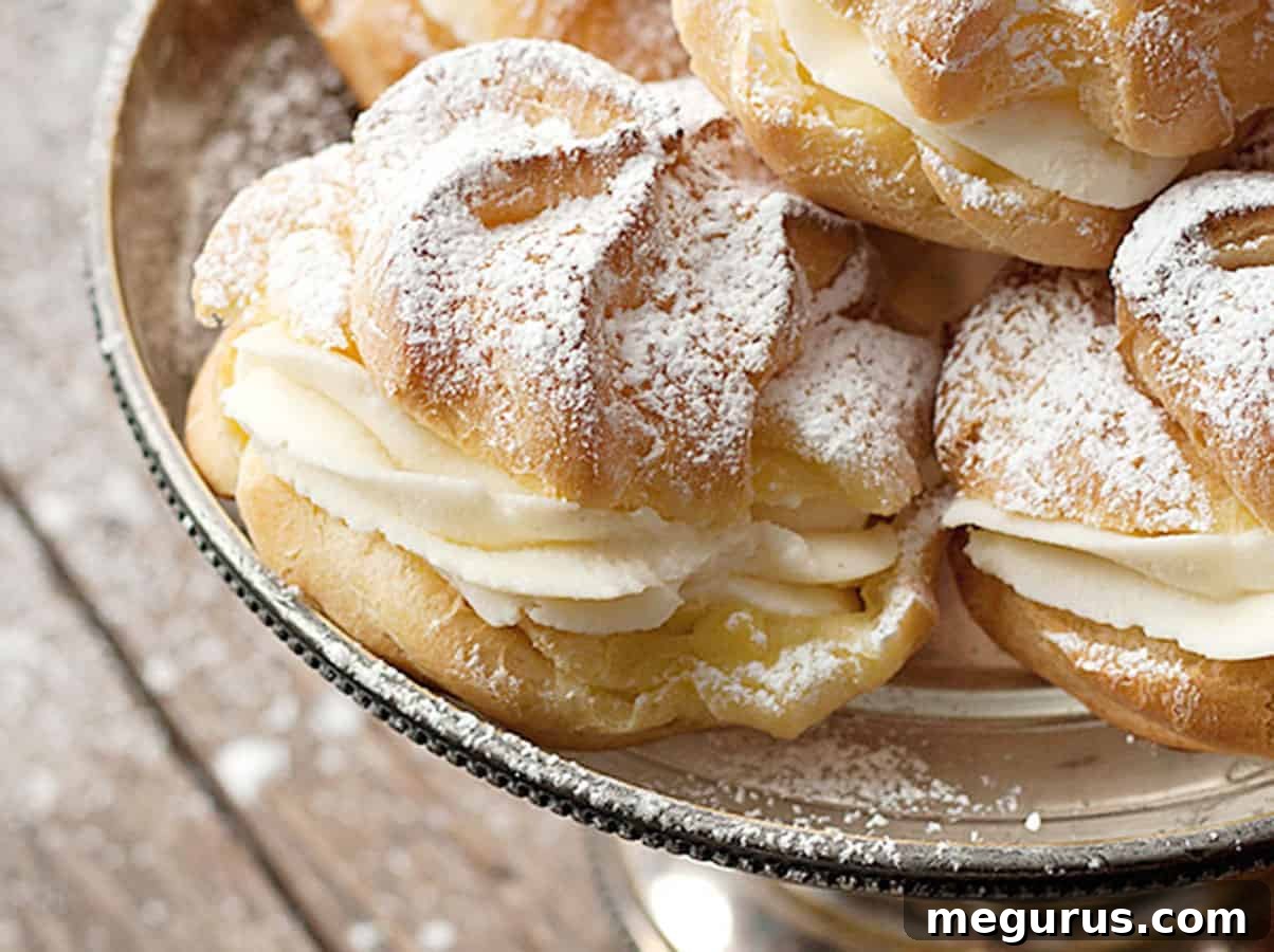 Delicate Cannoli Cream Puffs showcased on an elegant silver dessert stand, ready to be enjoyed.