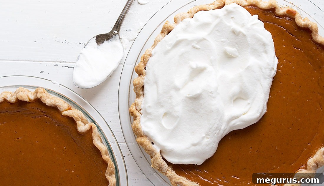 A slice of classic Canadian pumpkin pie being topped with fluffy homemade whipped cream, ready to be served.