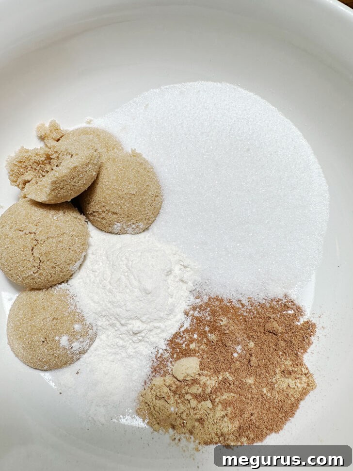 Dry ingredients for pumpkin pie filling, including brown sugar, white sugar, flour, cinnamon, nutmeg, ginger, and salt, in a mixing bowl.