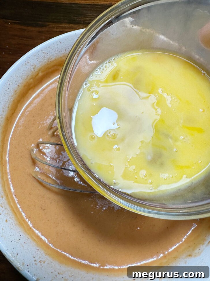 Lightly beaten eggs being added to the mixed pumpkin pie batter.