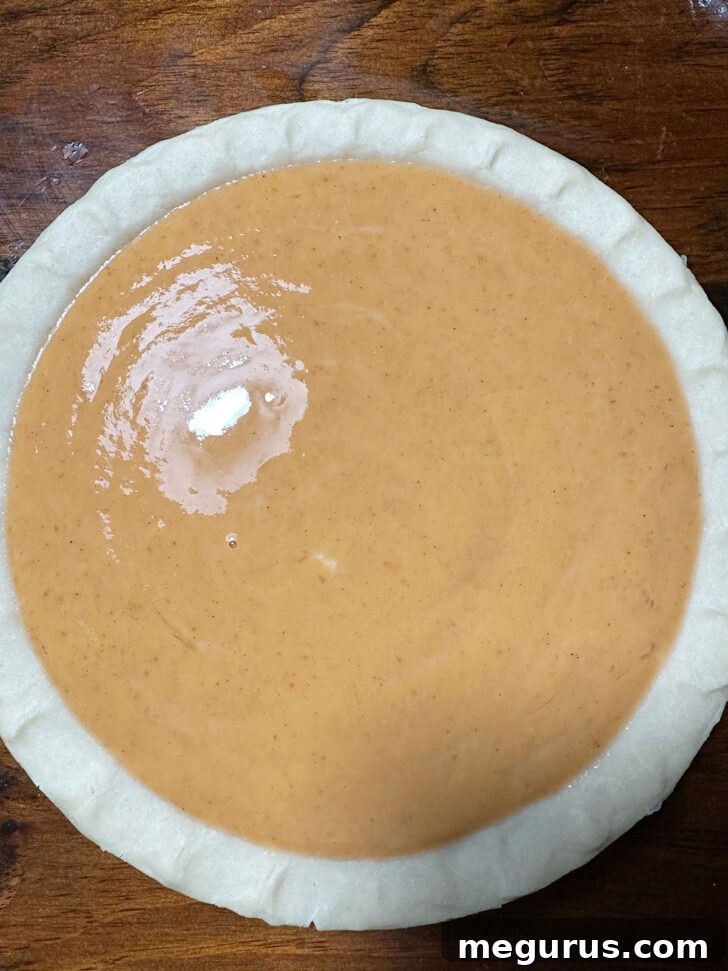 Smooth pumpkin pie filling poured into an unbaked deep-dish pie shell.