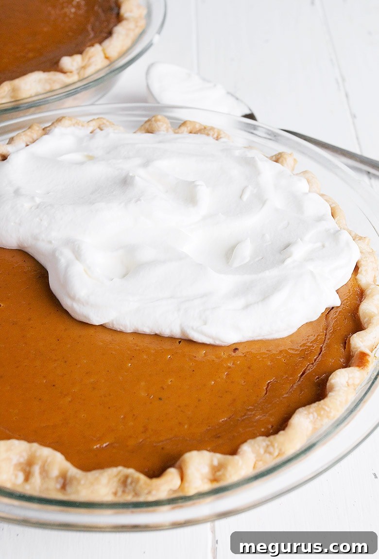 A freshly baked pumpkin pie, ready to be sliced, showcasing its inviting golden crust and smooth filling.