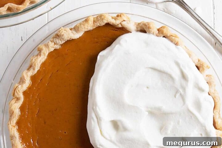 A visually appealing pumpkin pie topped with whipped cream, ready to be served from a recipe card.
