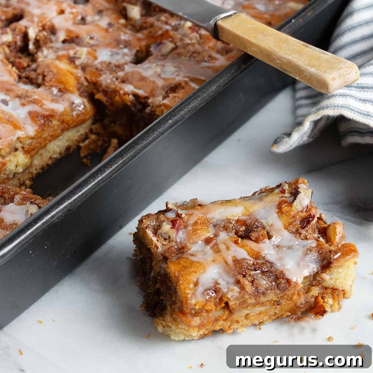 A slice of sour cream pumpkin cake next to the full cake in a pan