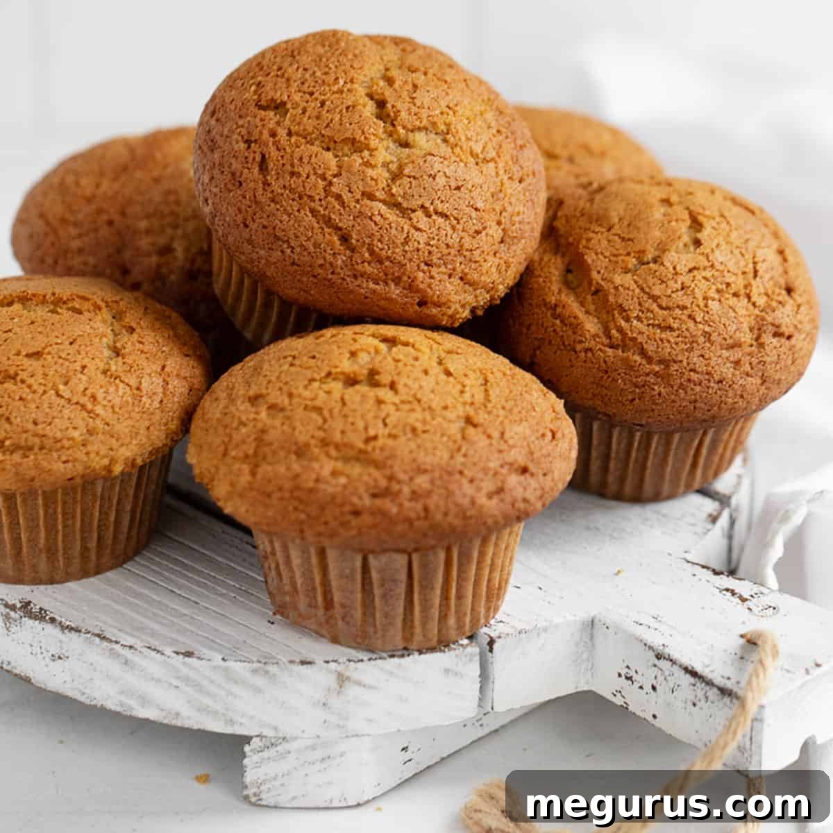 Fluffy pumpkin muffins with domed tops on a white serving board