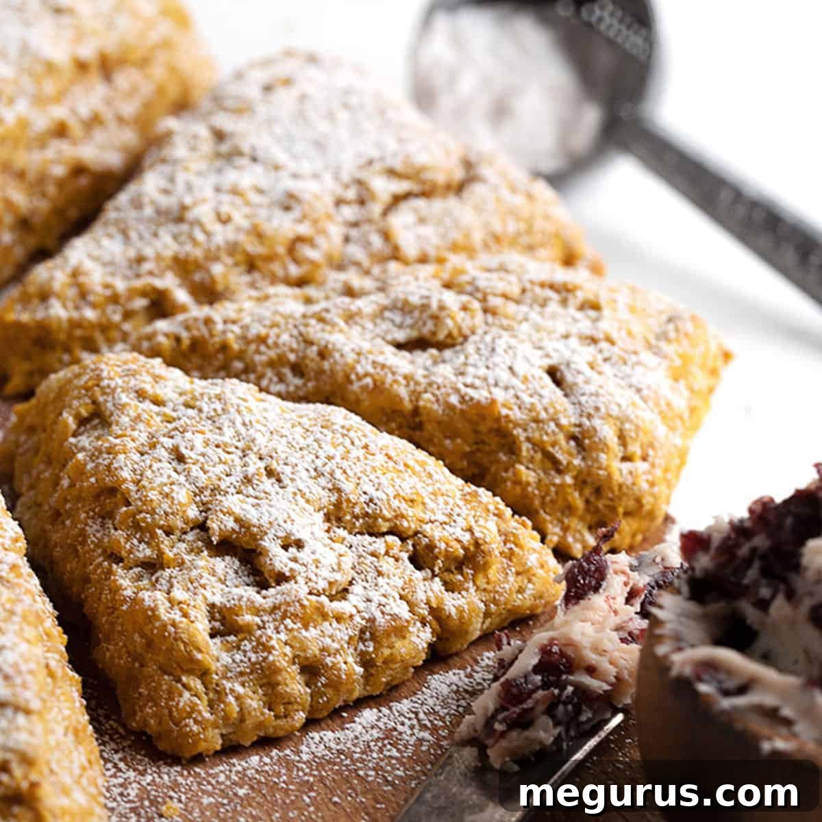 Freshly baked pumpkin scones on a cutting board, some with cranberry butter