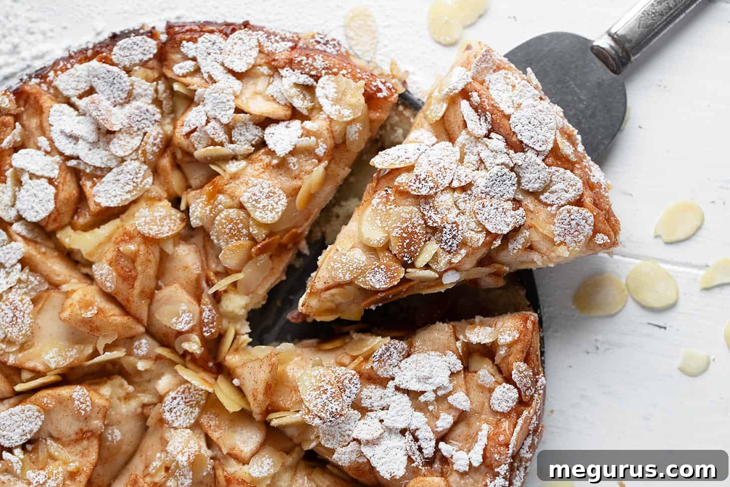Sliced Bavarian Apple Torte, showcasing layers of shortbread, jam, cream cheese, and apples with almonds