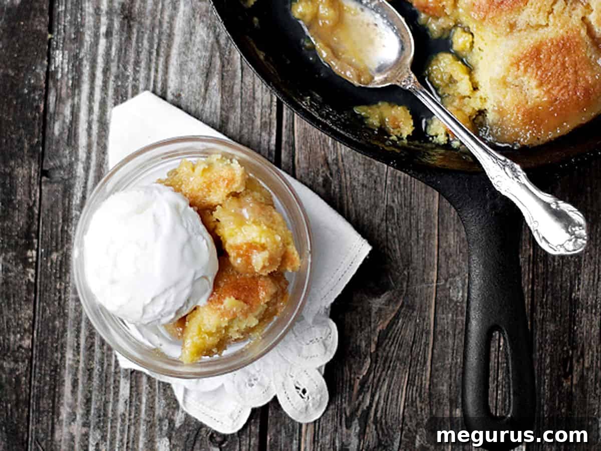 Golden maple syrup pudding cake in a cast iron skillet, with a serving in a bowl topped with vanilla ice cream
