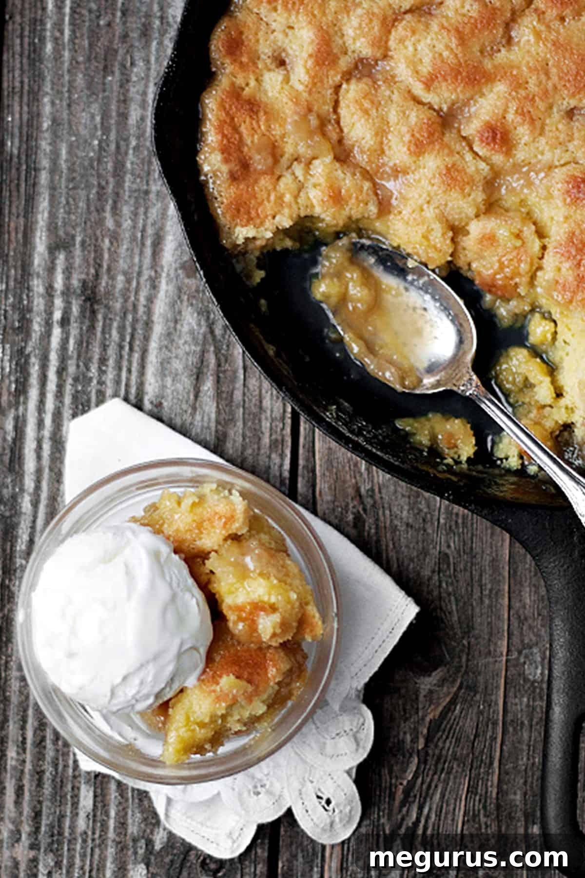 Close-up of maple syrup pudding cake in a cast iron skillet, with a scoop removed into a bowl