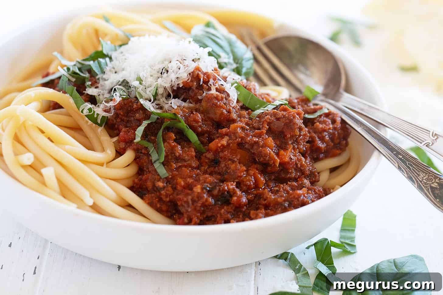 classic Italian meat sauce with spaghetti in bowl, garnished with fresh basil