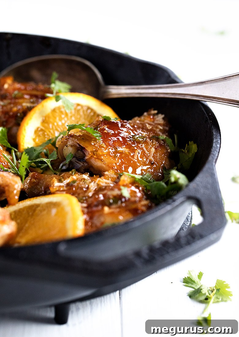 orange glazed chicken thighs in cast iron skillet, golden brown and sticky