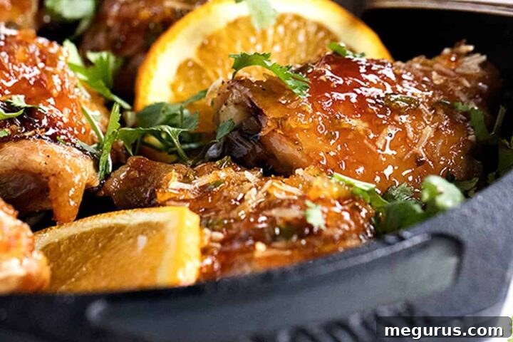 sticky orange chicken in skillet with orange slices